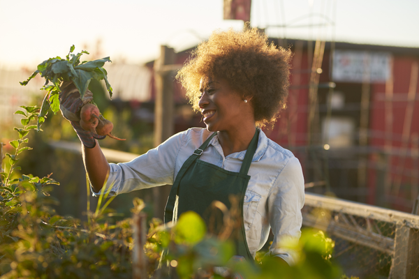 A woman wearing an apron holds a carrot, promoting dental health through nutrition.