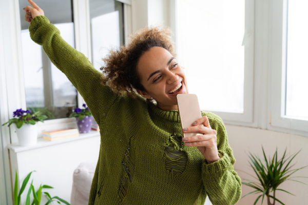 A woman joyfully holds her phone, displaying her dental health, with a focus on her radiant smile.
