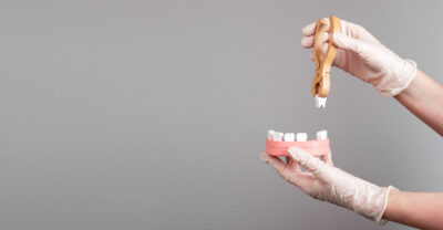 A dental professional in white gloves is holding a toothbrush, symbolizing oral health care.