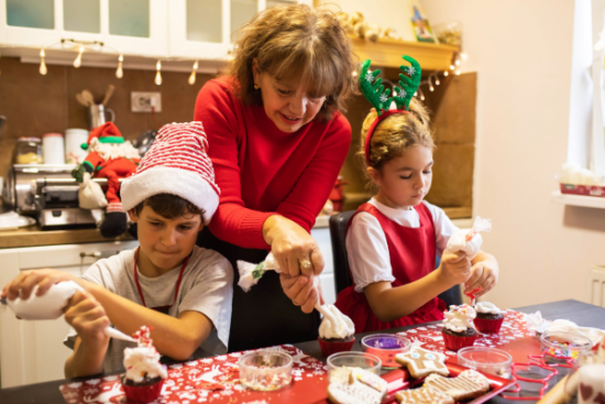 Woman and two children decorating holiday cookies together in a kitchen, demonstrating family time and healthy smiling