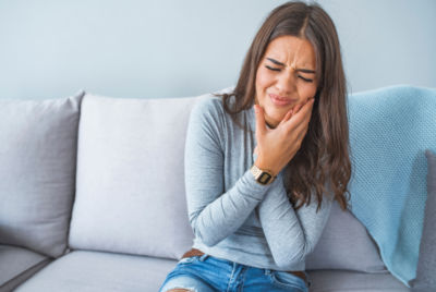Woman holding jaw in pain.