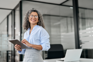 a businesswoman smiling and holding a tablet standing in an office