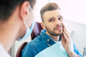 a man holding his mouth and speaking to his dentist